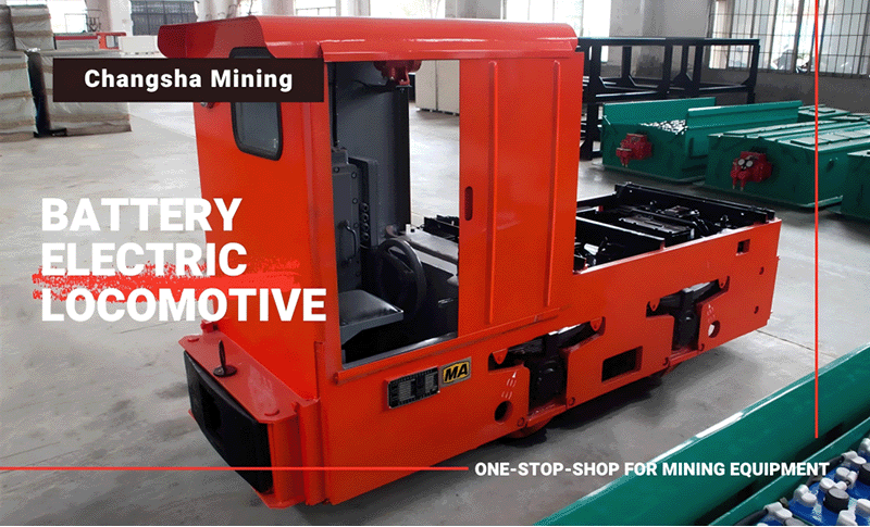 A red battery locomotive chassis and a row of batteries neatly placed next to it A red battery locomotive chassis and a row of batteries neatly placed next to it