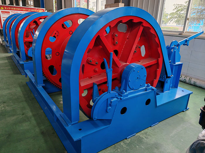 A newly manufactured mine hoist winch with blue and red paint finish, ready for delivery, displayed in the factory workshop.