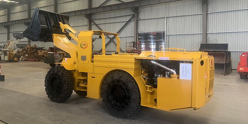 A robust scoop tram stands in snowy terrain beside a Christmas tree and gift boxes, symbolizing it as the ultimate holiday gift for the mining industry.