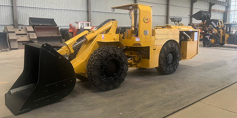A robust scoop tram stands in snowy terrain beside a Christmas tree and gift boxes, symbolizing it as the ultimate holiday gift for the mining industry.