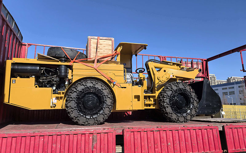 A robust scoop tram stands in snowy terrain beside a Christmas tree and gift boxes, symbolizing it as the ultimate holiday gift for the mining industry.