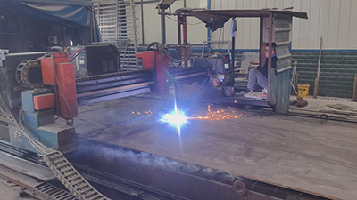 Abstract geometric illustration of steel locomotive frame fabrication with orange welding sparks and CNC cutting elements in a bold industrial style.