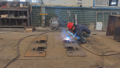 Abstract geometric illustration of steel locomotive frame fabrication with orange welding sparks and CNC cutting elements in a bold industrial style.