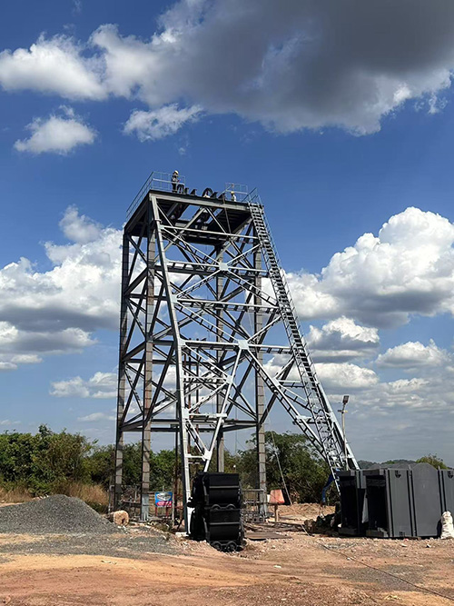 Mine hoisting system with industrial drum and headframe at sunset underground mining site.