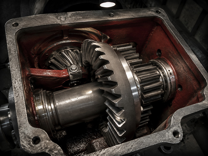 Close-up view of a heavy-duty two-stage reduction gearbox for a 5-ton mining electric locomotive, showcasing the thick spiral bevel gears and robust steel construction inside the axle-hung housing.