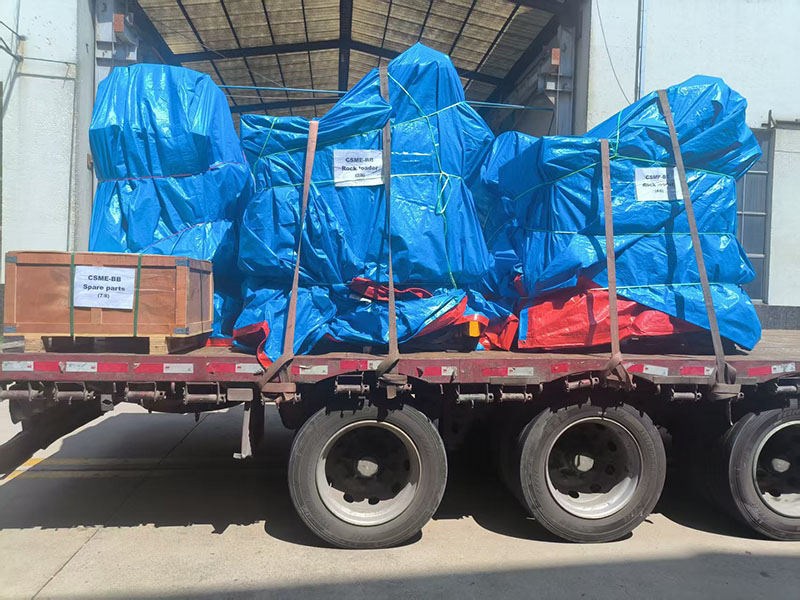 Five ZQ-15 pneumatic rock loaders wrapped in blue tarpaulins and secured with orange straps inside a 40ft high-cube container for sea shipment. Five ZQ-15 pneumatic rock loaders wrapped in blue tarpaulins and secured with orange straps inside a 40ft high-cube container for sea shipment.